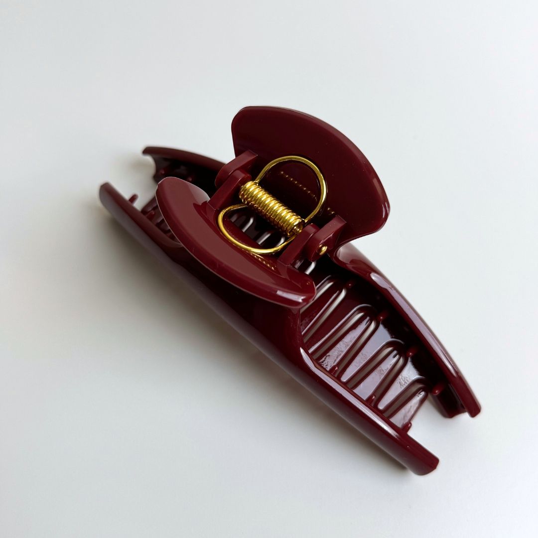 Maroon hair clip with gold spring on a white background