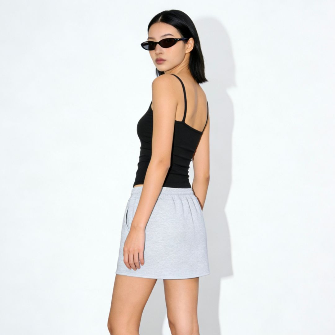 Woman wearing a black top and light gray skirt on a white background