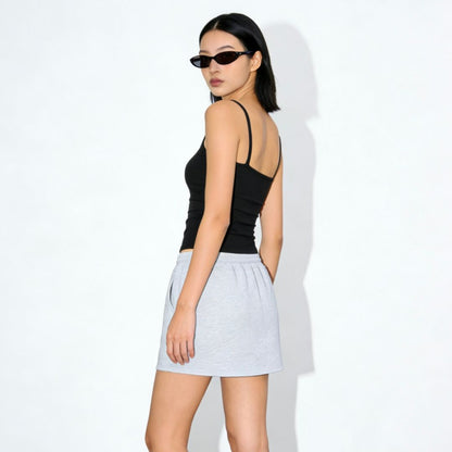 Woman wearing a black top and light gray skirt on a white background