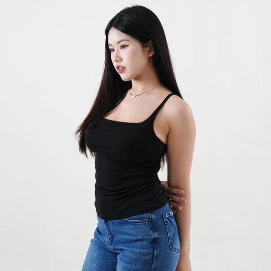 Woman wearing a black tank top and blue jeans against a white background