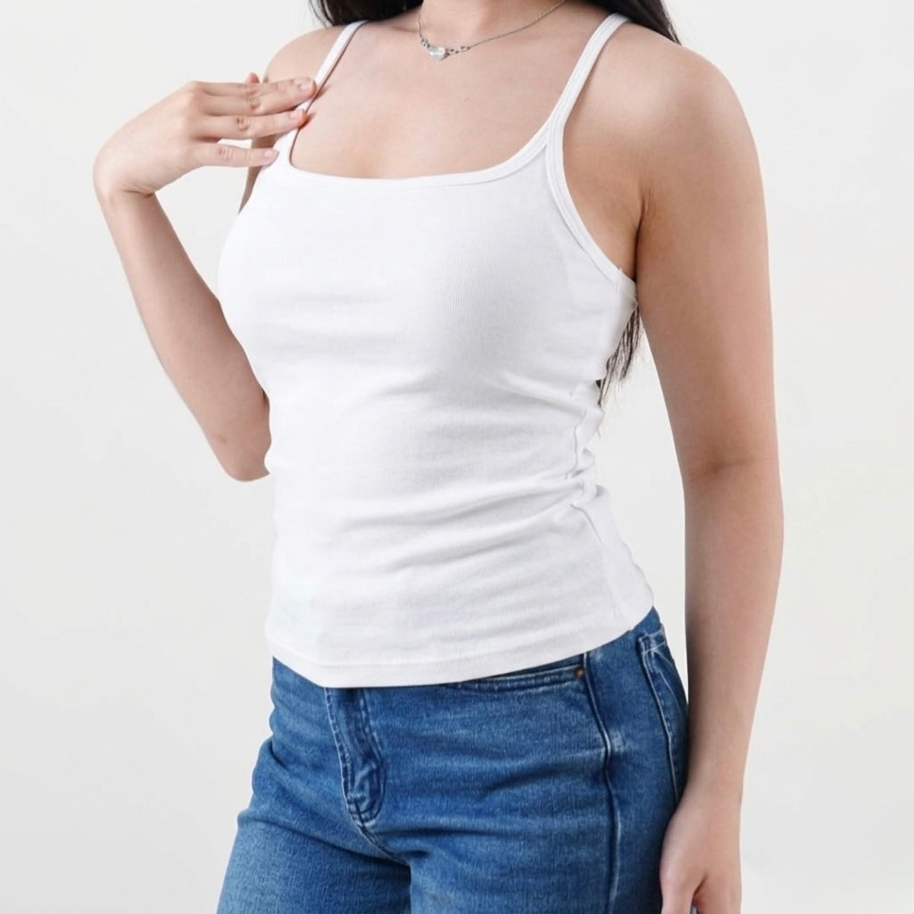 Person wearing a white tank top and blue jeans on a plain background