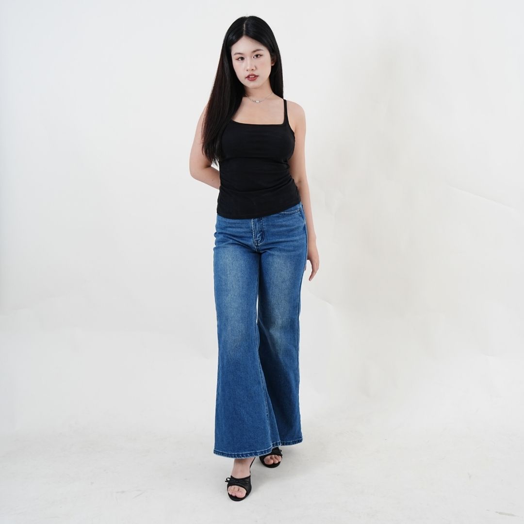Woman wearing a black tank top and blue jeans on a white background