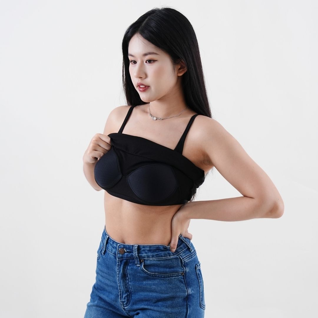 Woman wearing a black bralette and blue jeans on a white background